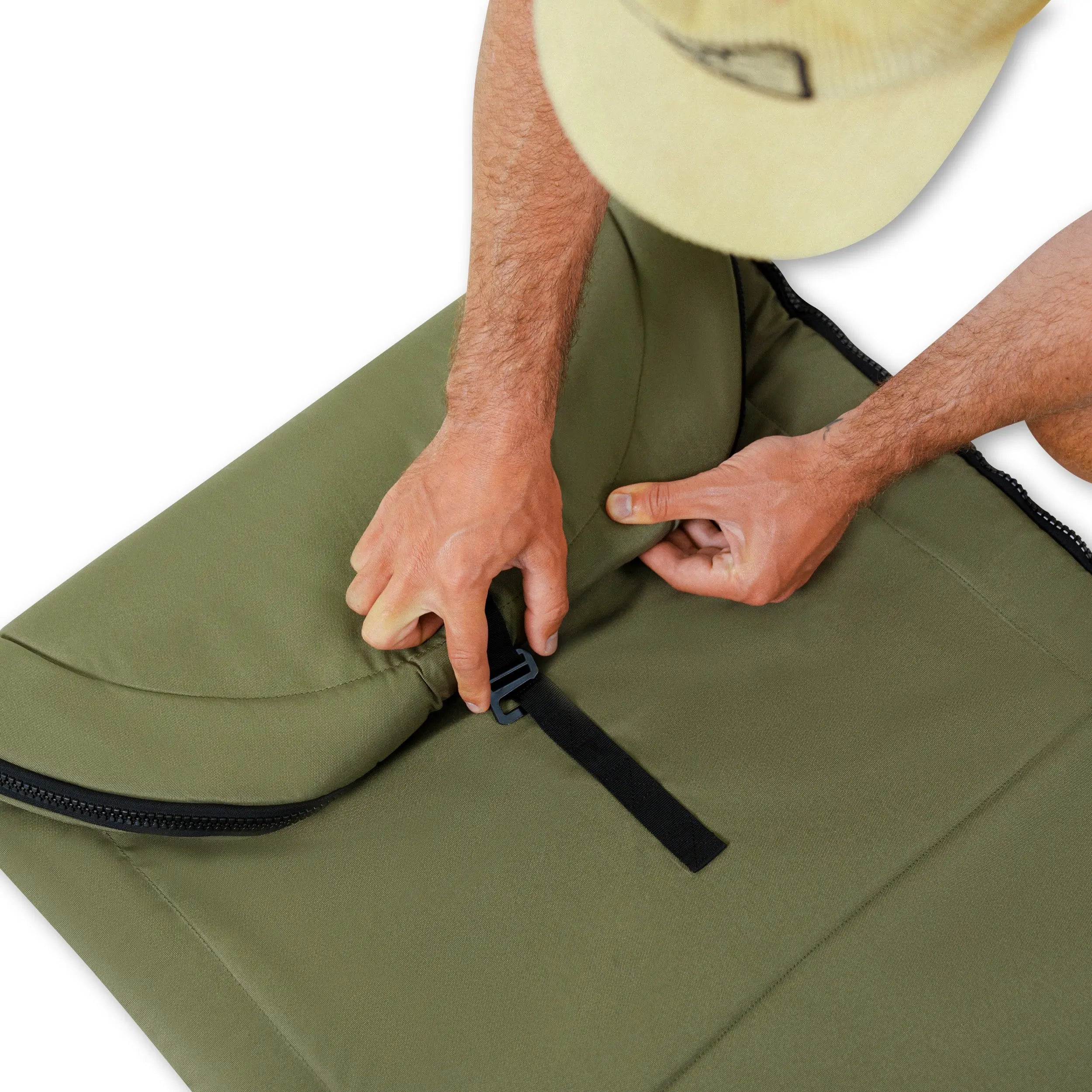 Person adjusting a green surf bag with a white background