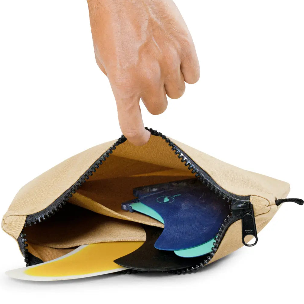 Hand opening a tan fin pouch with a colorful fish design on a white background