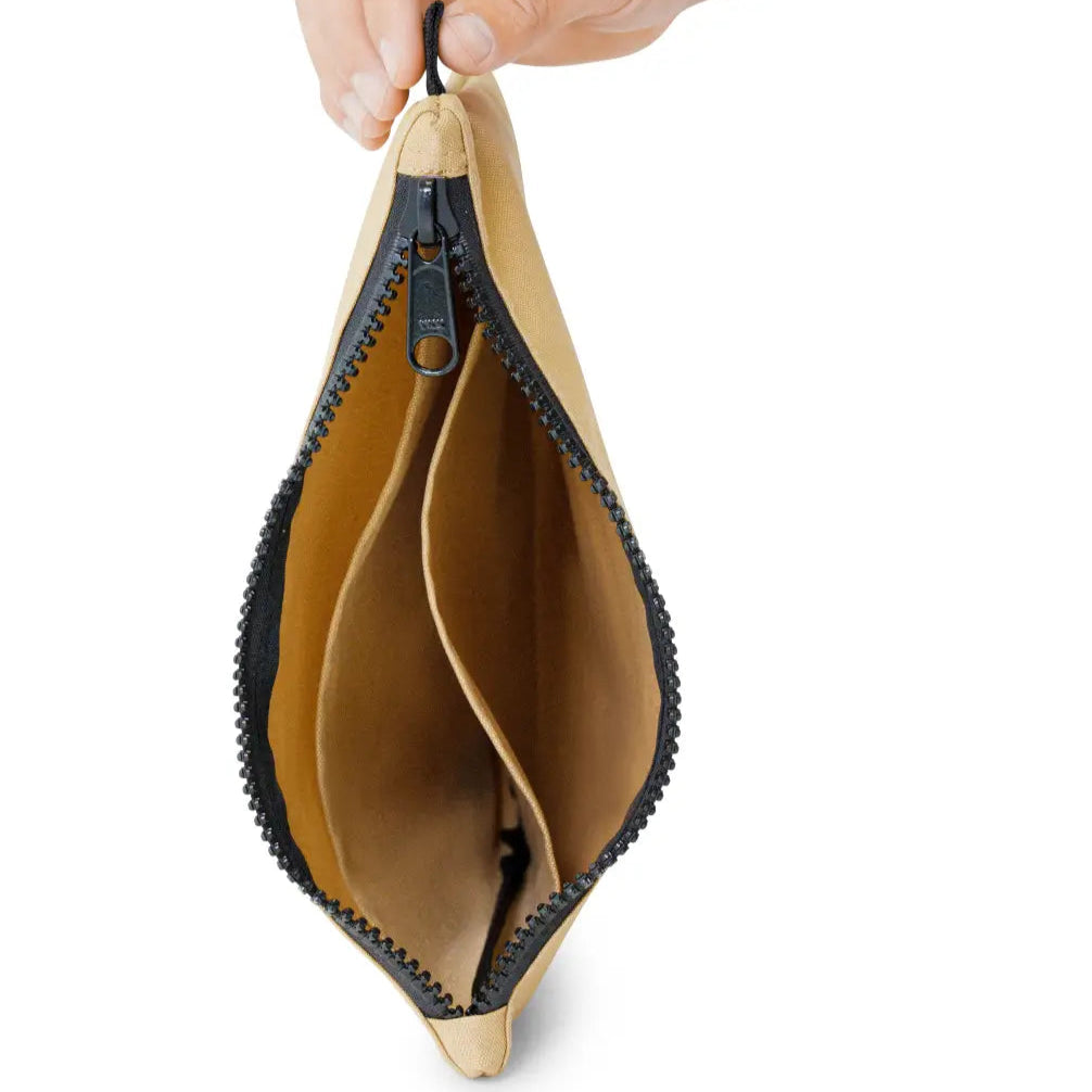 Beige pouch with black zipper held by a hand on a white background